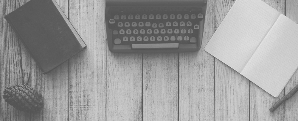 A black and white photo of a typewriter on a wooden table.